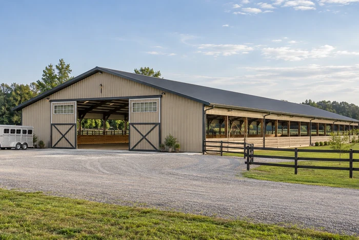 Covered riding arena with broad access doors and an open trailer approach. Covered riding arena with broad access doors and an open trailer approach.